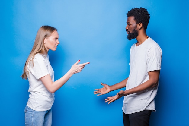 Foto pelea de pareja mixta joven aislado en la pared azul