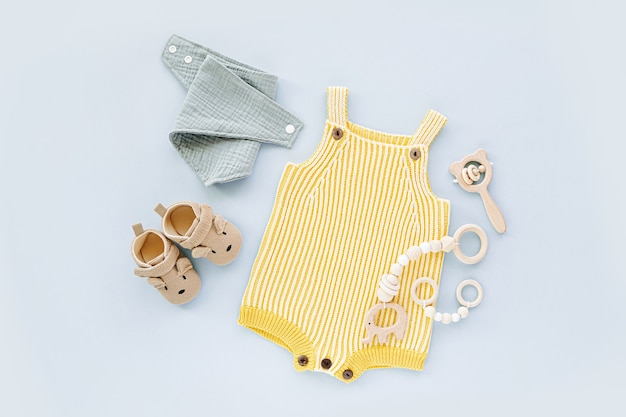 Pelele de punto amarillo con zapatitos, juguetes y complementos. Ropa de moda para recién nacidos