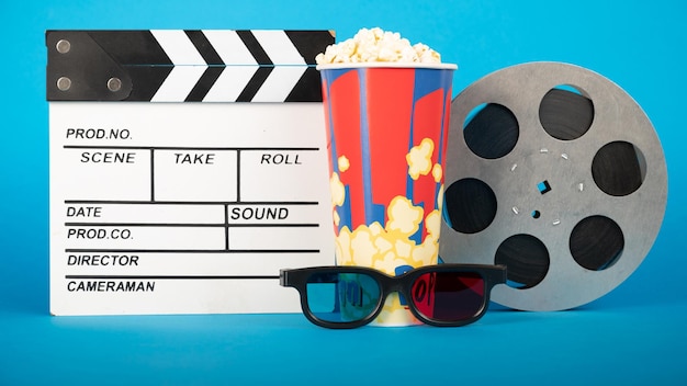 Película badajo palomitas de maíz gafas 3D y carrete de película sobre fondo azul Diseño de collage