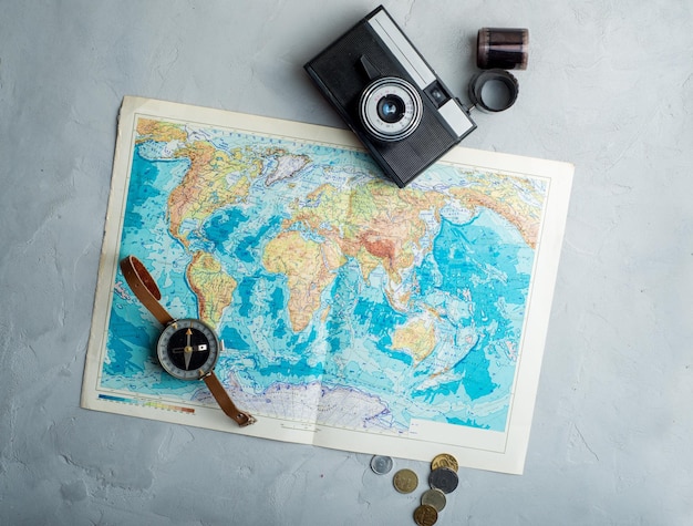 Película de cámara vintage de mapa mundial y monedas sobre un fondo de hormigón ligero