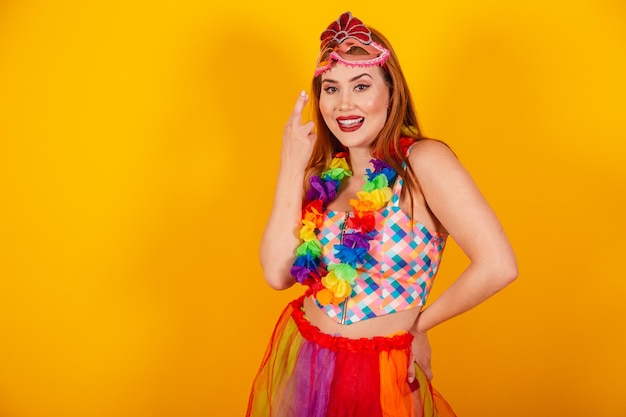 Pelirroja brasileña en ropa de carnaval con un collar de flores alrededor de su cuello con los dedos cruzados