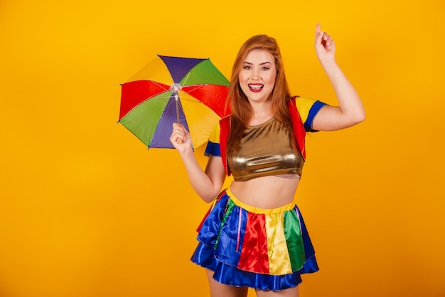 Pelirroja brasileña con ropa de carnaval frevo y colorida sombrilla bailando