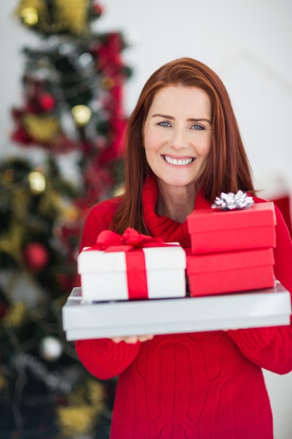 Pelirroja festiva con pila de regalos