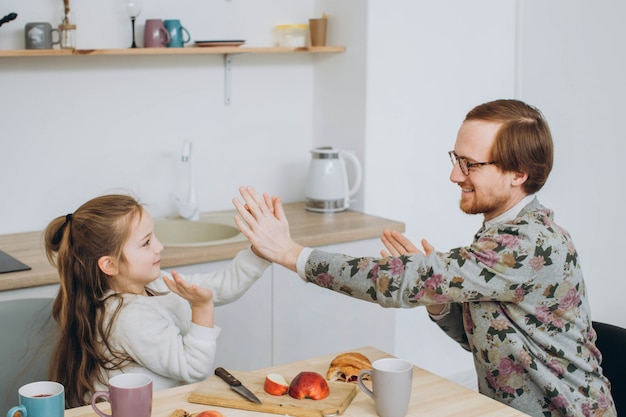 Pelirroja hipster padre e hija se divierten en la cocina.