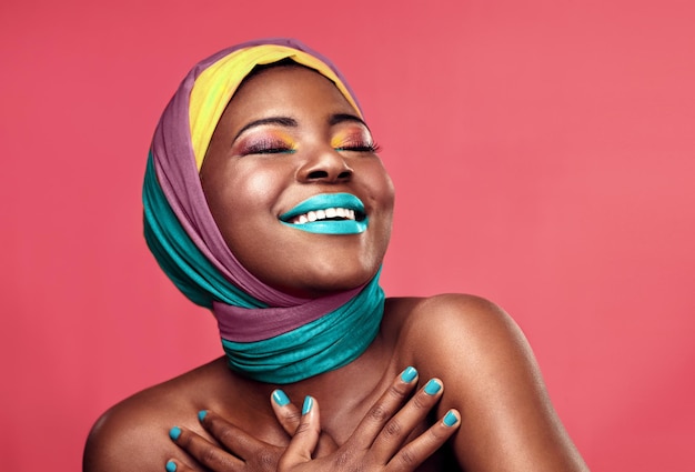 Pelo amor da cor Foto de estúdio de uma bela jovem sorrindo enquanto usava um turbante e maquiagem contra um fundo rosa