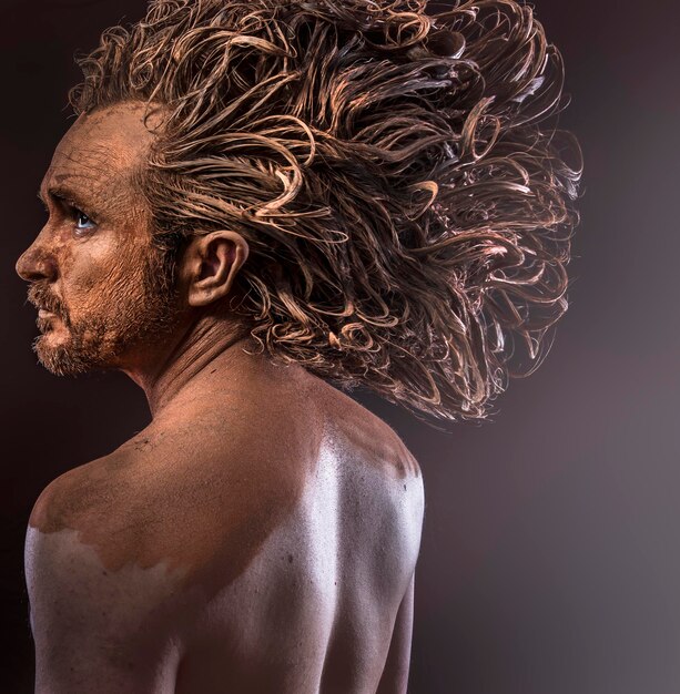 Pelo enorme, hombre salvaje, concepto tribal, tradiciones, cuerpo cubierto de barro.