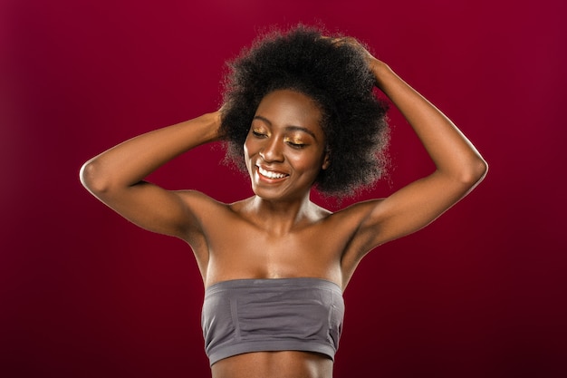 Pelo oscuro. Mujer morena alegre tocando su cabello oscuro mientras posa para una foto