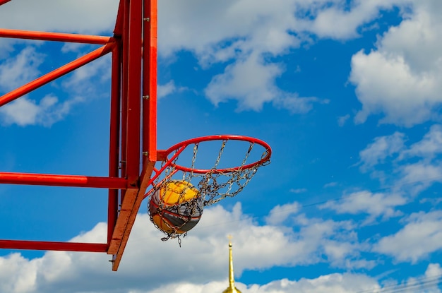 Una pelota en un aro de baloncesto contra el cielo.
