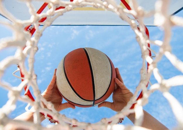 La pelota atraviesa el hombre de la canasta lanzando la pelota en las manos del aro y la clavada de baloncesto en la canasta