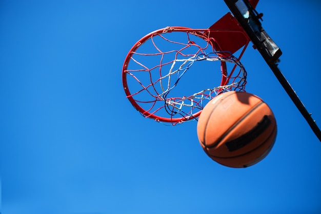 Pelota de baloncesto y aro aislado en el cielo azul