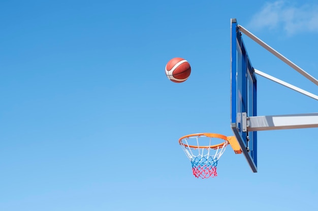 Una pelota de baloncesto en una red sobre un fondo de cielo azul La pelota golpeó el anillo Juego de equipo deportivo Éxito de victoria conceptual golpeando el deporte objetivo