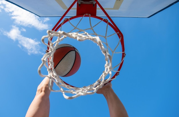 Pelota de baloncesto volando a través de la canasta en las manos de los jugadores ganando