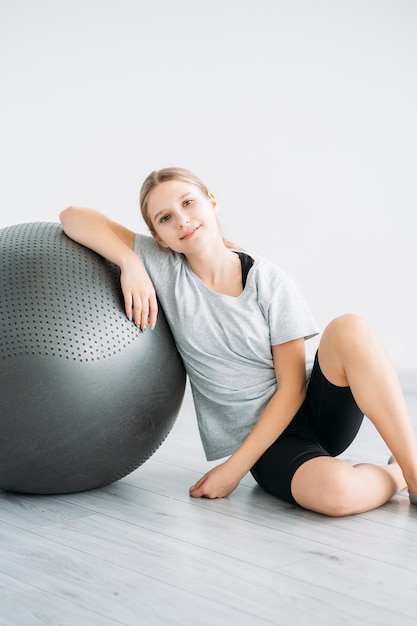 Pelota de ejercicio de niña de deporte de niño de entrenamiento de fitness en casa