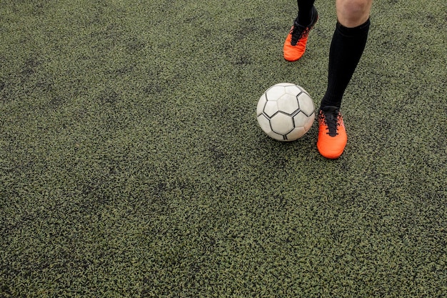pelota de fútbol con sus pies en el campo de fútbol
