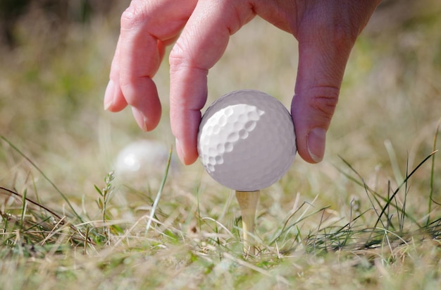 Pelota de golf blanca que se está instalando en el tee