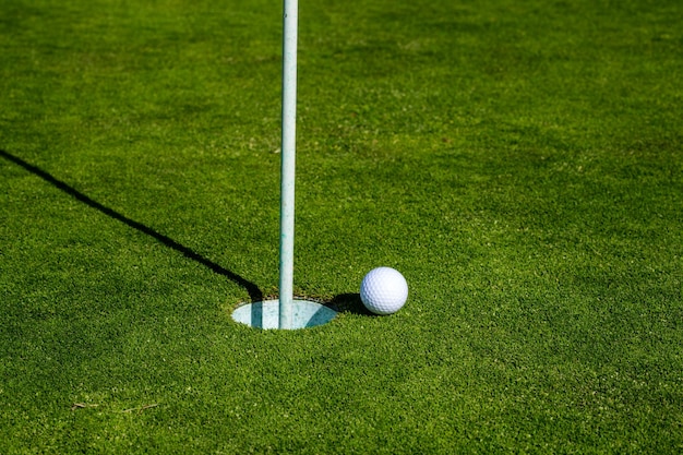 Pelota de golf en el borde de la copa en el fondo de hierba hoyo de golf pelota de golf en el césped deporte fondo de golf wi