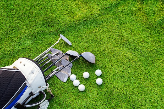 Pelota de golf y club de golf en bolsa sobre hierba verde