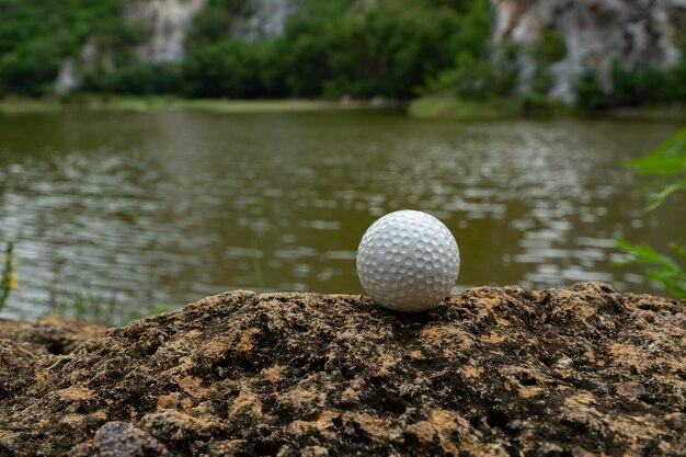 Pelota de golf en roca cerca del pequeño lago