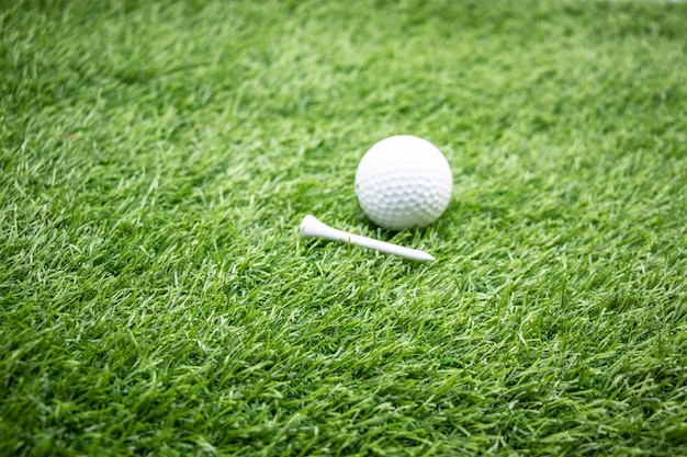 La pelota de golf y el tee está en la hierba verde