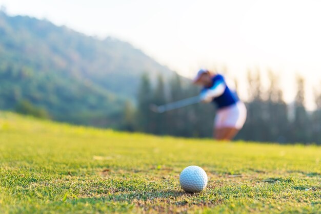 Pelota de golf y tee en el fondo de hierba verde