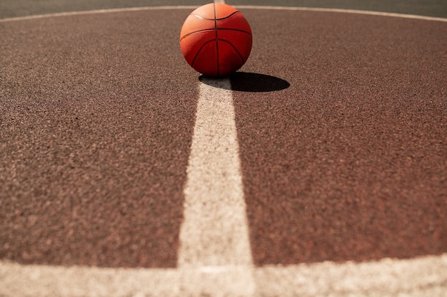 Pelota para jugar al baloncesto en el centro de la línea blanca vertical en un estadio o campo moderno