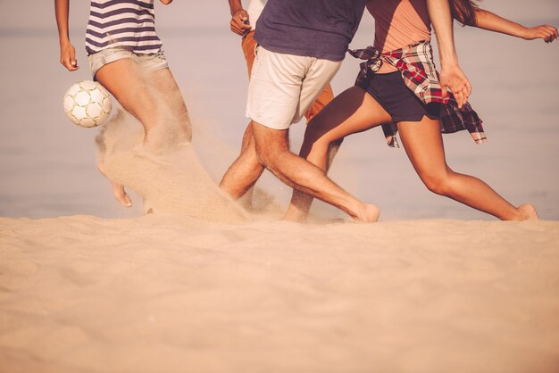 Pelota de playa en movimiento. Imagen recortada de jóvenes jugando con una pelota de fútbol en la playa