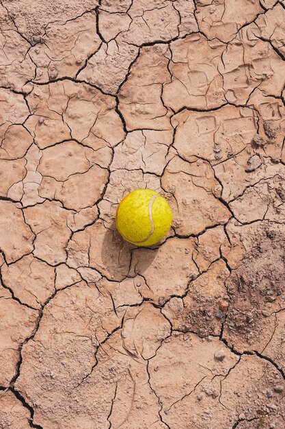 Foto pelota de tenis amarilla en el suelo del desierto el calentamiento global