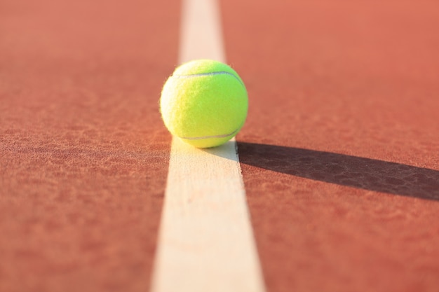 Pelota de tenis de color amarillo verdoso brillante en la línea.