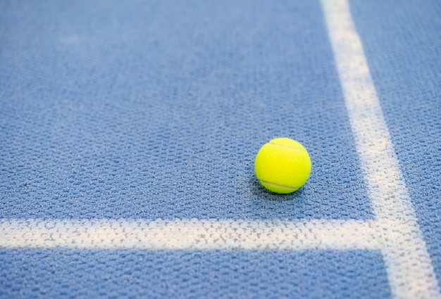 Foto pelota de tenis cubierta en cancha de tenis, línea blanca, superficie azul, espacio de copia