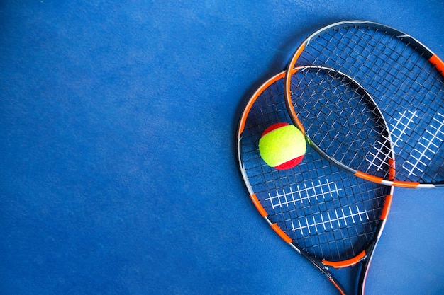 Pelota de tenis para niños y raquetas de tenis sobre fondo azul Foto horizontal