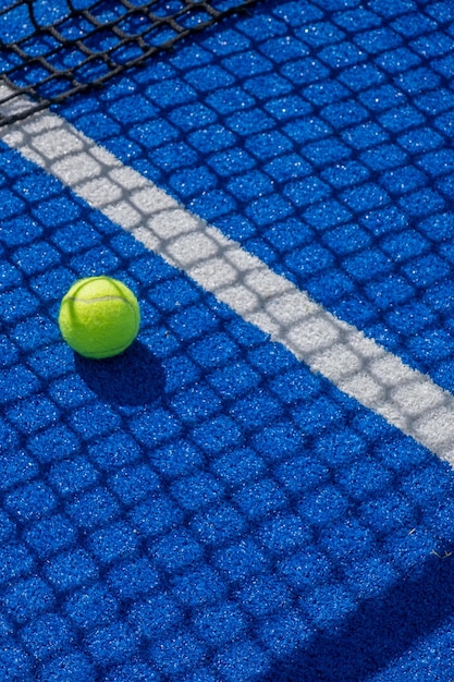 pelota de tenis de paleta a la sombra de la red de una cancha de tenis de paddle azul concepto deportivo de raqueta