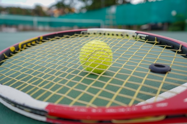 pelota de tenis y raqueta en cancha dura