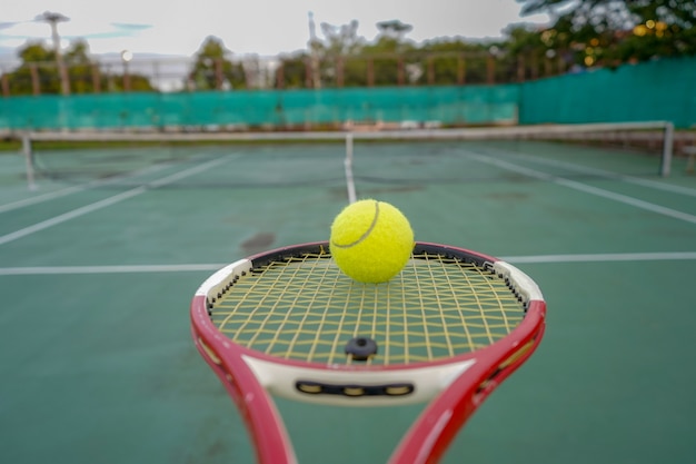 pelota de tenis y raqueta en cancha dura