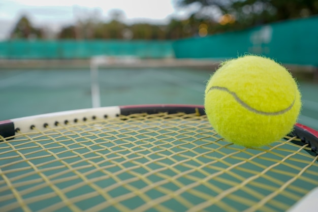 pelota de tenis y raqueta en cancha dura