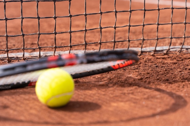 Pelota de tenis y raqueta por red en cancha de arcilla Concepto de competencia de torneo deportivo