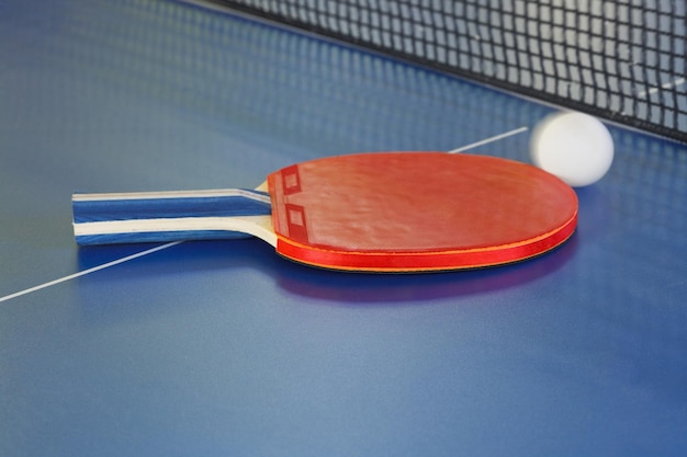 Pelota de tenis de raqueta roja en mesa de ping pong azul