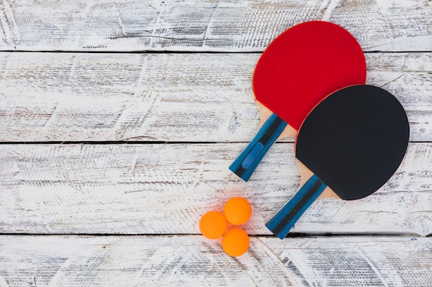 Pelotas de ping pong y raqueta de madera sobre fondo blanco de madera