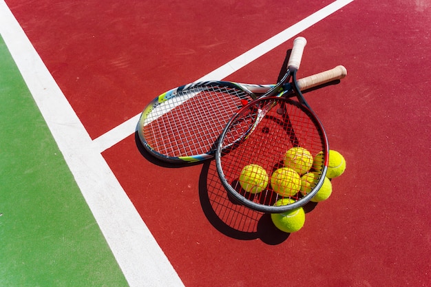 Pelotas de tenis y raqueta en la cancha de césped.