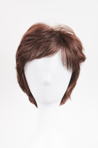 Peluca morena de aspecto natural en la cabeza del maniquí blanco Cabello marrón corto en el soporte de la peluca de plástico aislado en fondo blanco vista delantera