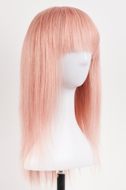 Foto peluca rubia de aspecto natural en cabeza de maniquí blanca cabello largo cortado en el soporte de peluca de plástico aislado en fondo blanco