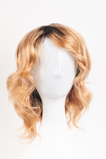 Peluca rubia de aspecto natural en cabeza de maniquí blanco Corte de pelo de longitud media en el soporte de peluca de plástico aislado en la vista frontal de fondo blanco