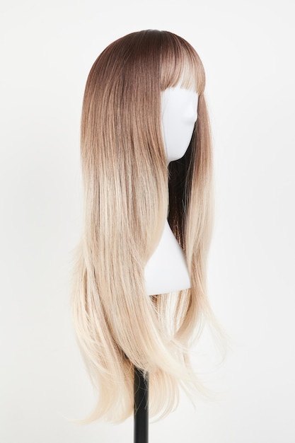 Peluca rubia de aspecto natural sobre cabeza de maniquí blanco Pelo largo en el soporte de peluca de plástico aislado sobre fondo blanco