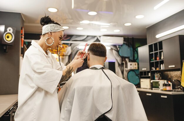 Una peluquera corta el cabello de un hombre en una peluquería Peluquería profesional para hombres Peluquería