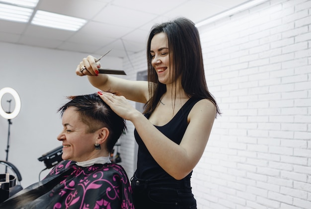 Una peluquera corta cuidadosamente las puntas del cabello de la mujer en un salón de belleza, close-up