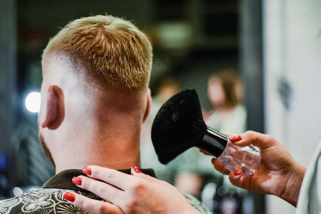 La peluquera elimina los residuos del cabello con un cepillo después del corte