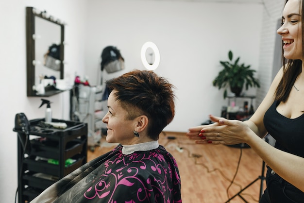 Una peluquera hace un peinado para una clienta en un salón de belleza moderno. El arte de la peluquería.