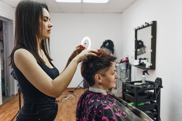 Una peluquera hace un peinado para una clienta en un salón de belleza moderno. El arte de la peluquería.