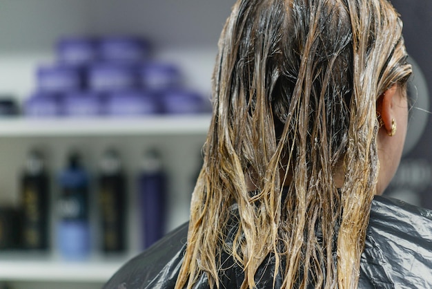 la peluquera tiñe el cabello de una mujer en el salón.