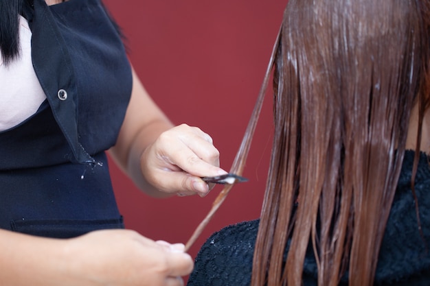 Peluquería aplicando tratamiento capilar. Aplicar crema de color en el cabello.