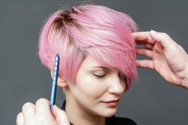 Foto peluquería comprobando el cabello rosado femenino